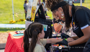 Event staff member assisting a child with an activity at a family day event
