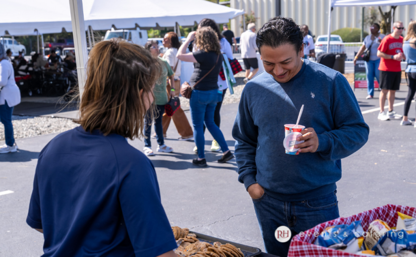 Guests chatting outdoors near white tents at a family day event