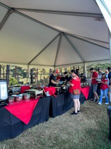 Large-scale catering setup with buffet lines under an outdoor event tent by RH Events & Catering
